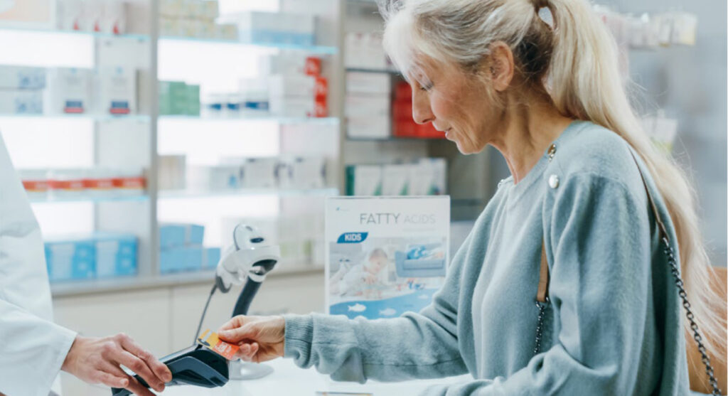 Older woman at the cash register at a pharmacy paying for her medication.