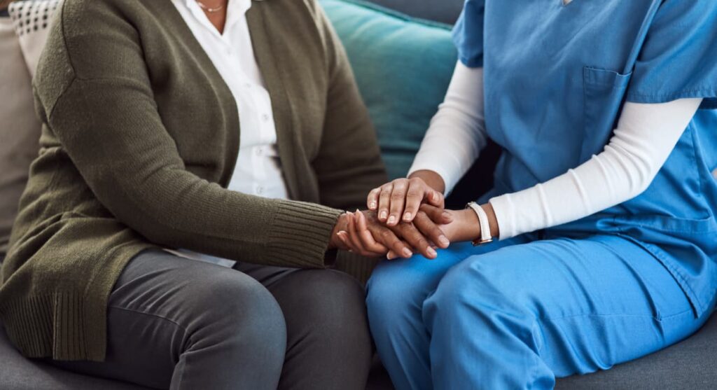 A medical professional holding the hand of an elderly patient