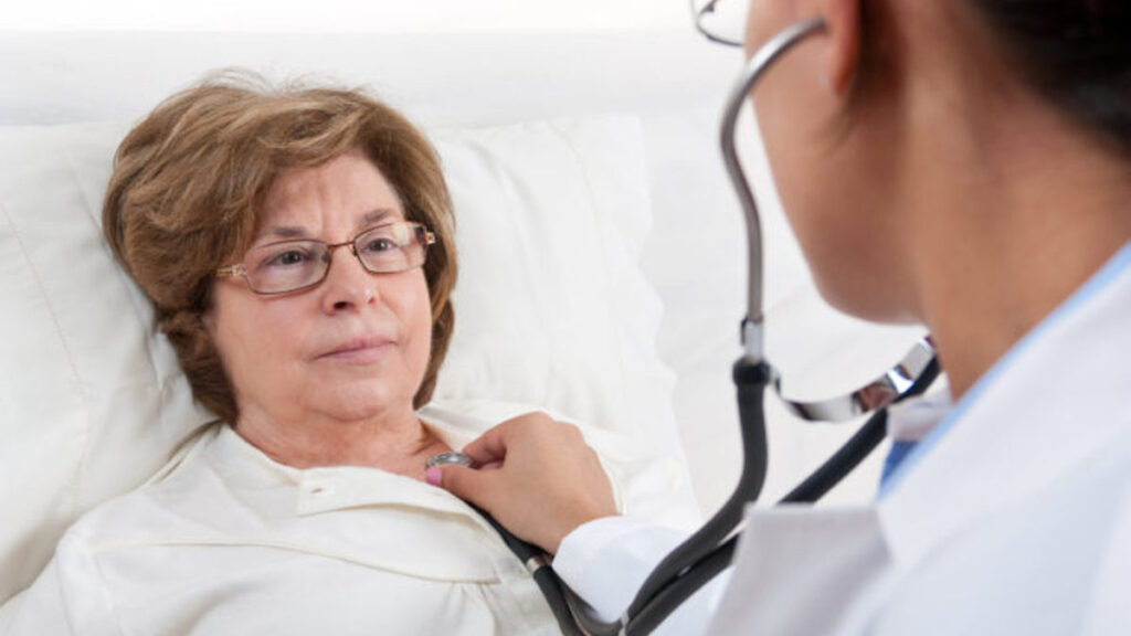 A doctor checking a recovering senior patient's heart with a stethoscope